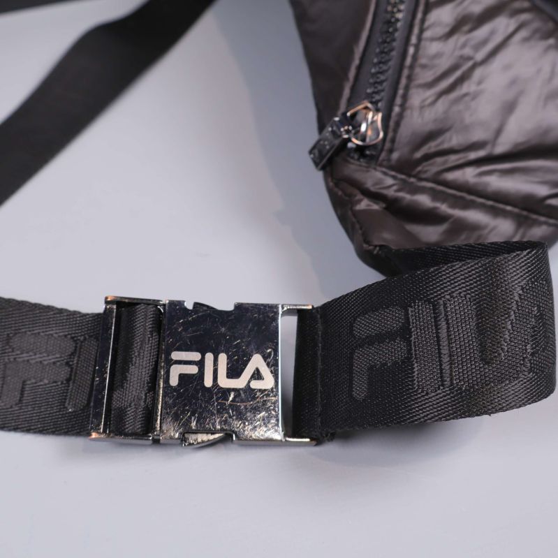 Metallspänne på svart rem med FILA-logotyp i fokus
