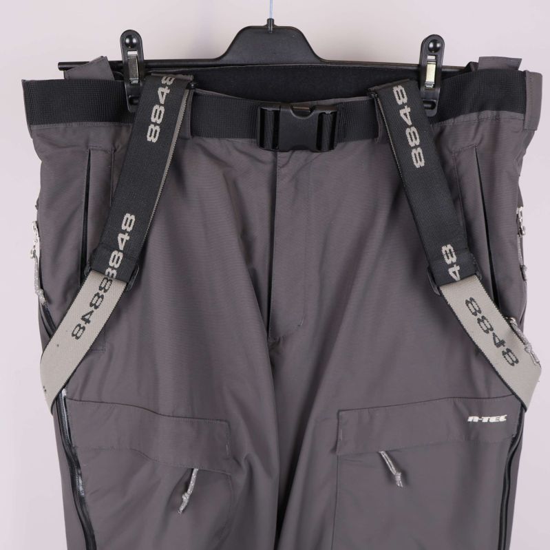 Närbild på midja och hängslen med logga fram