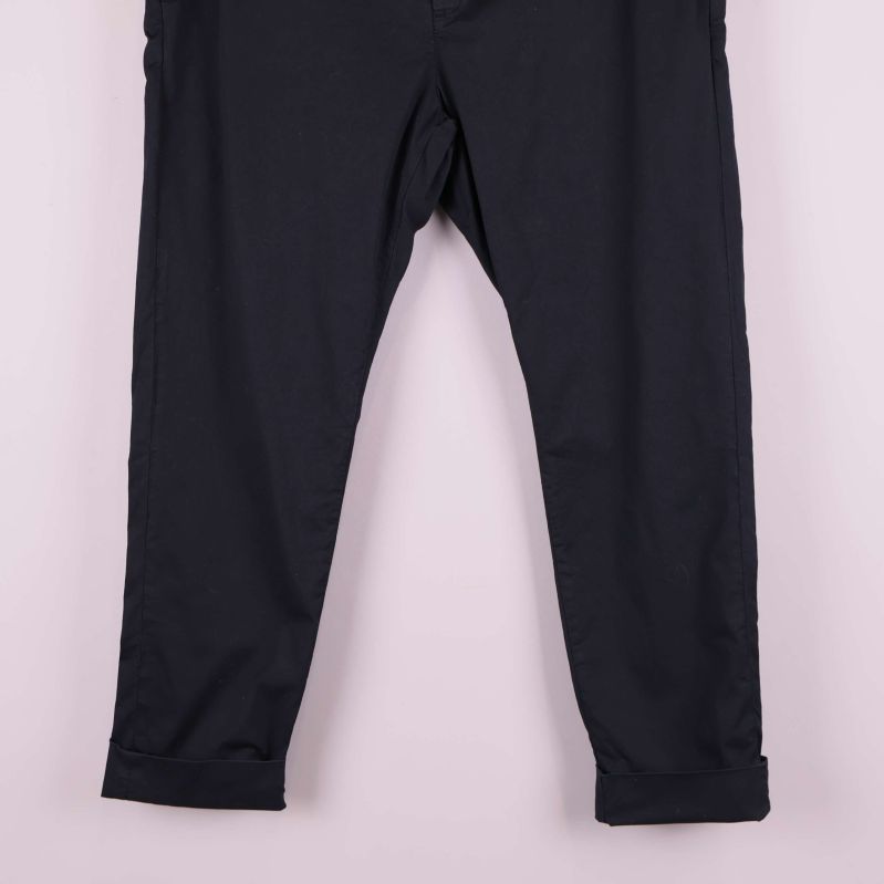 Närbild på raka ben med uppvikta benslut på svarta byxor