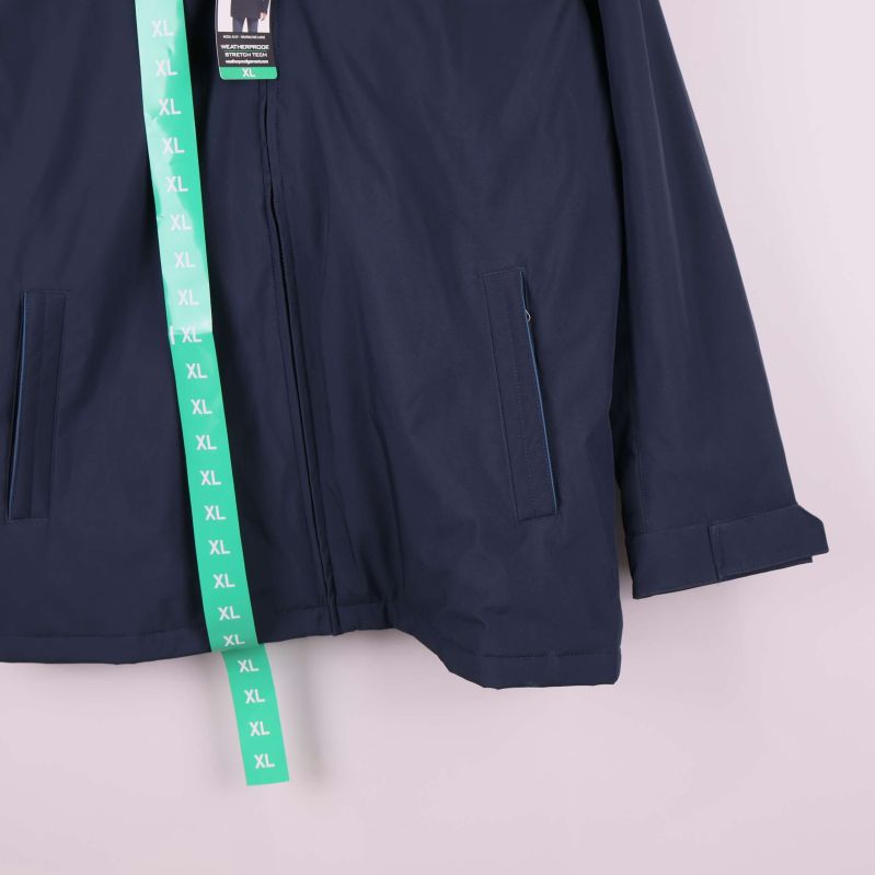 Närbild på jackans fickor och nederdel i mörkblått tyg