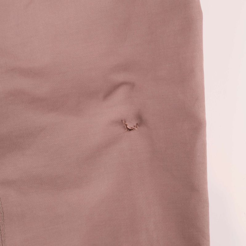 Slitet hål vid ärmbågen på vänster ärm av jackan