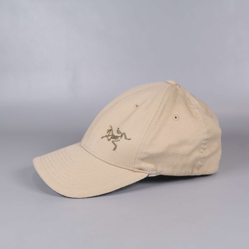 Sidan av beige keps och broderad logotyp visas