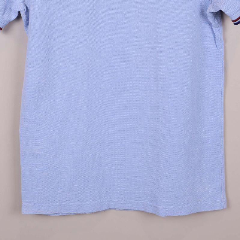 Nedre delen av ljusblå pikétröjan visas