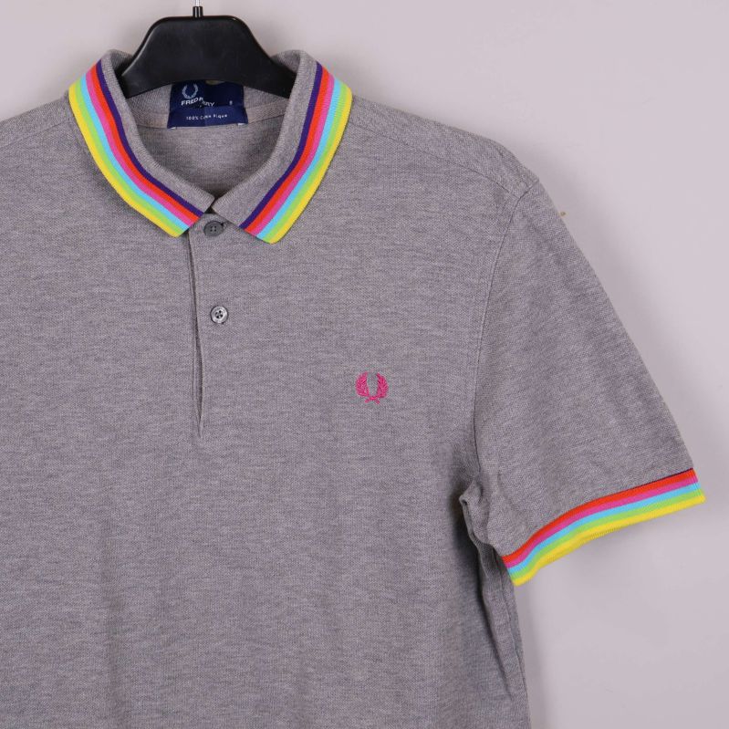 Närbild på pikétröjans krage och ärm med regnbågsdetaljer