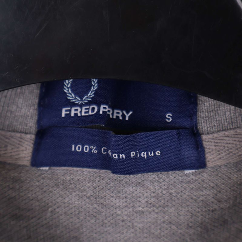 Närbild på etikett med Fred Perry och storlek S