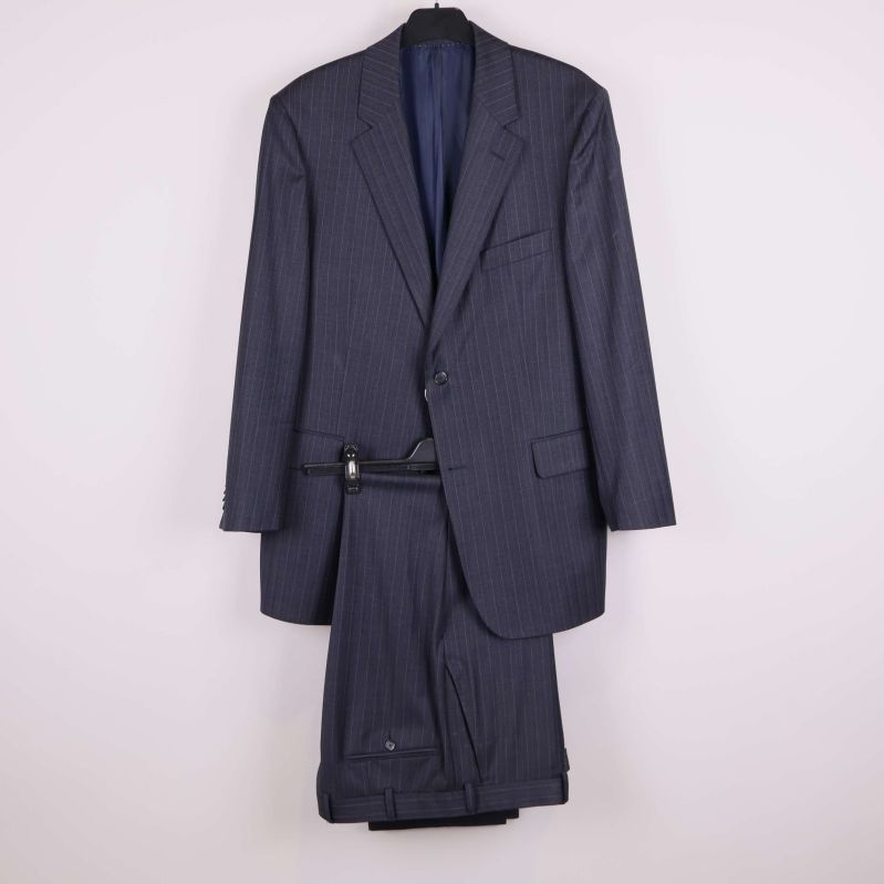 Mörk kritstrecksrandig kostym på galge mot ljus bakgrund