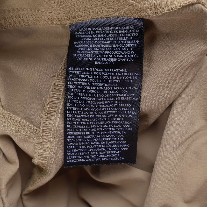 Materialetikett i beige friluftsbyxa visar sammansättning