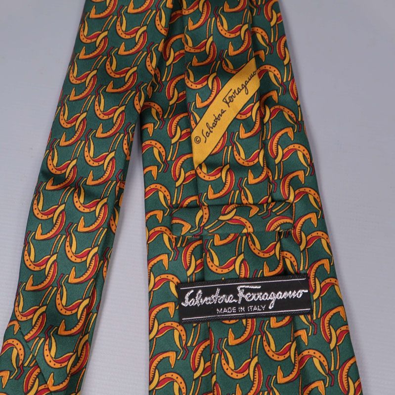 Närbild på Ferragamo-logga och gul märkning på grön slips