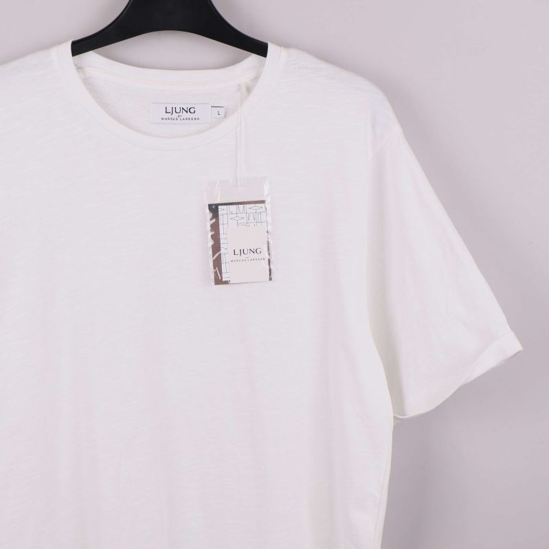 Vit t-shirt i närbild med hängande tagg framtill