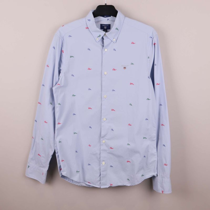 Ljusblå skjorta med små broderade flaggor framifrån