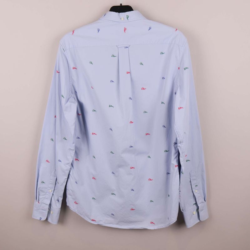 Ljusblå skjorta med broderade flaggor bakifrån