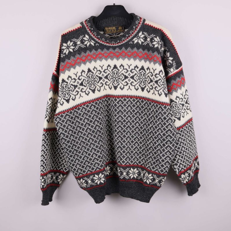 Stickad tröja med nordiskt mönster i svart, vitt och rött på galge