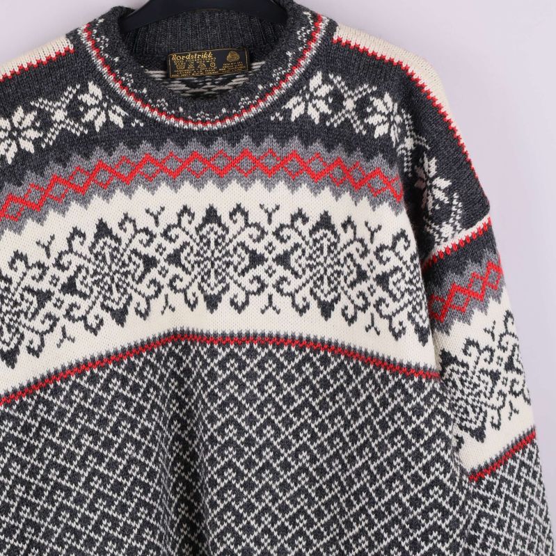 Närbild av tröjans överdel med snöflingemönster och röda detaljer