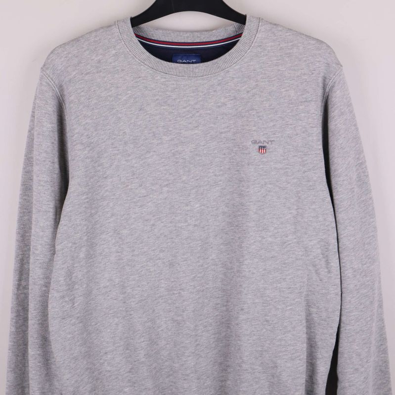 Närbild av grå sweatshirt med broderat emblem