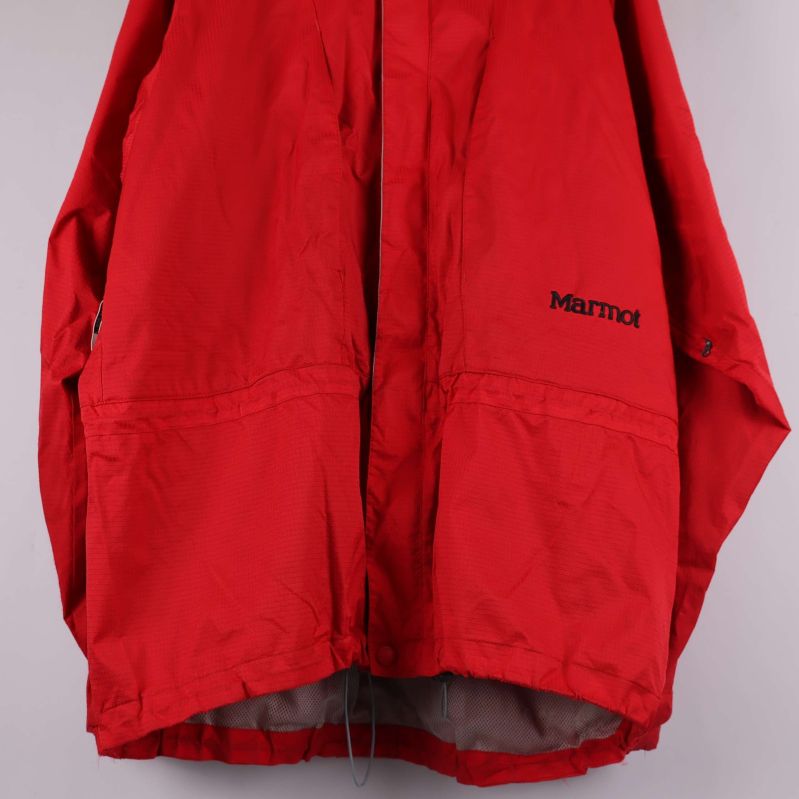Närbild på nedre framsidan av röd jacka med Marmot-logga
