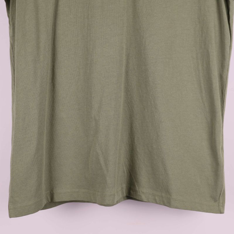 Detalj av nederkant och sidsöm på olivgrön t-shirt