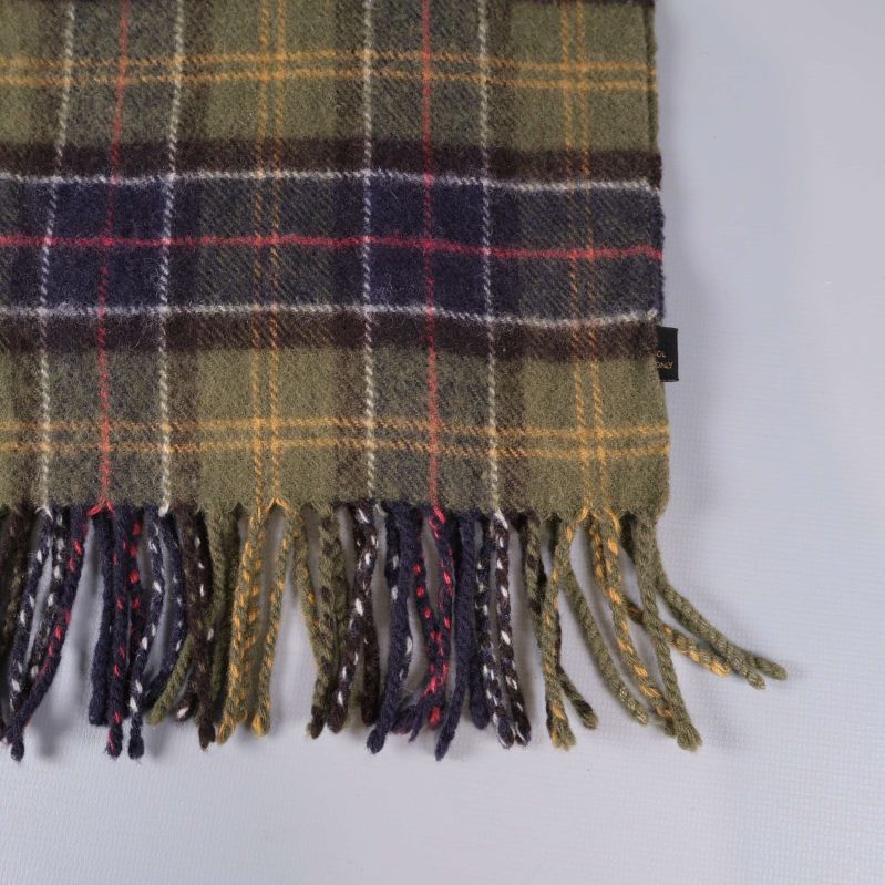 Närbild på fransar och rutmönster på halsduken