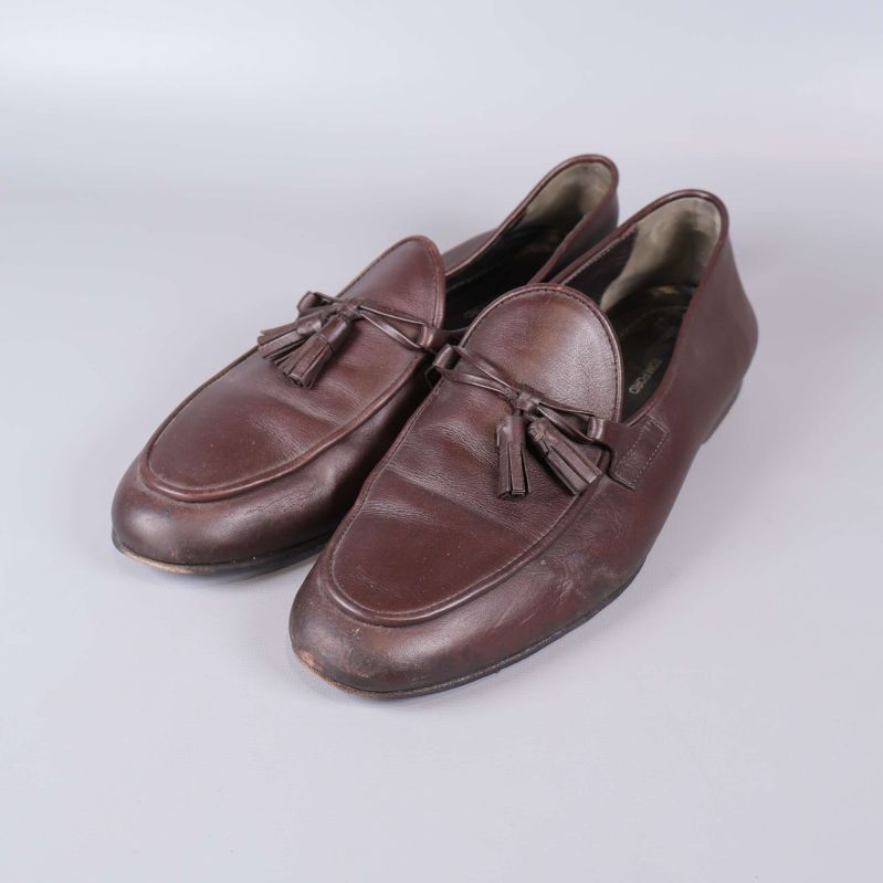 Par bruna loafers med tofsar fotade snett framifrån