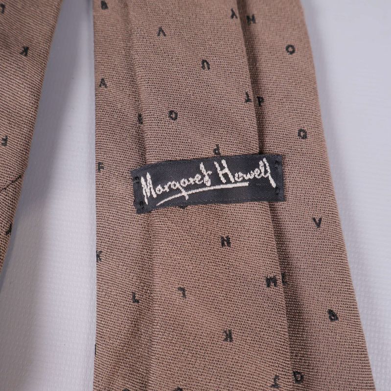 Närbild på svart varumärkesetikett Margaret Howell på slipsen