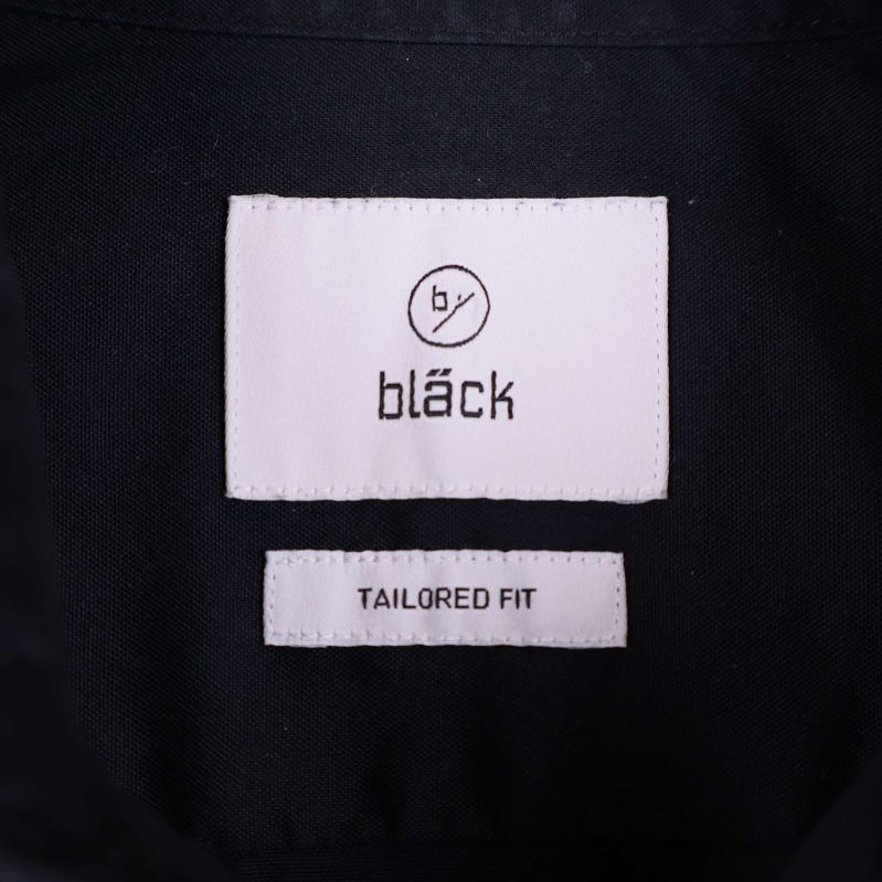 Närbild på etikett med texten by bläck tailored fit