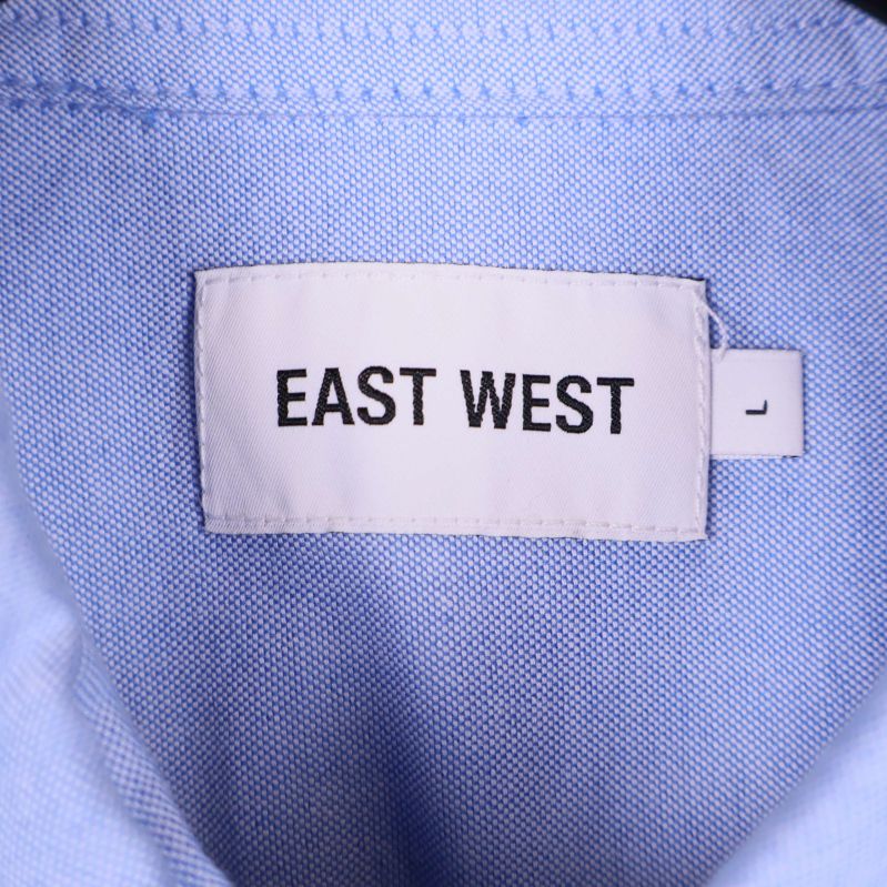 Närbild på vit etikett med texten EAST WEST i nacken