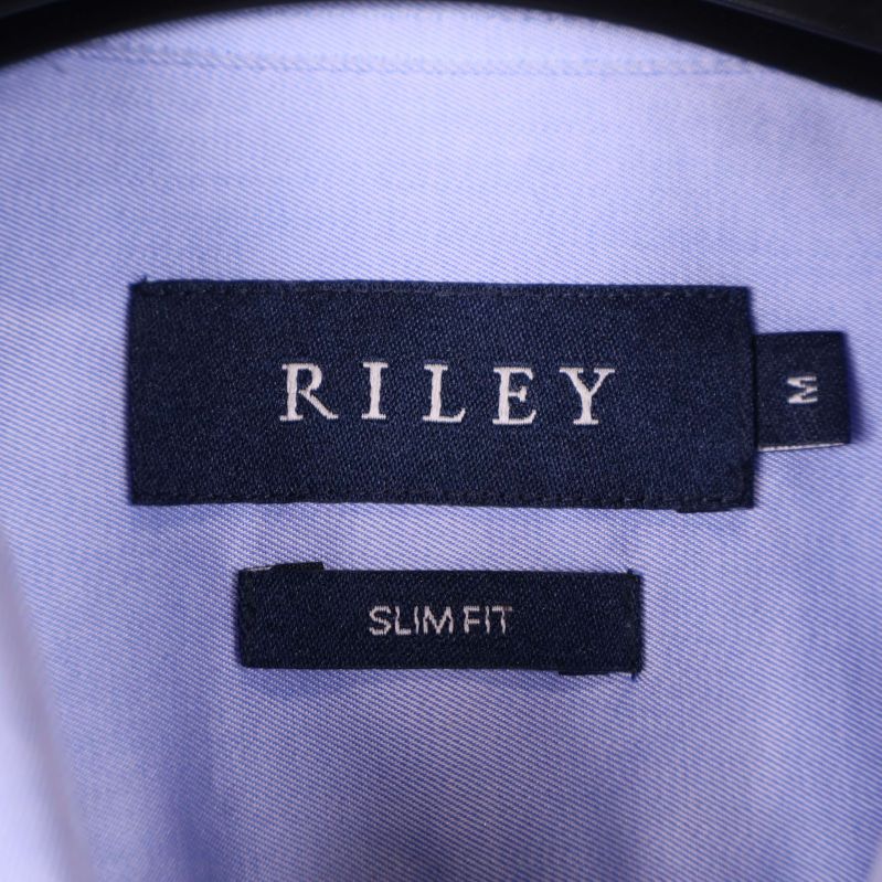 Närbild på Riley-logotyp på insidan av skjortkragen