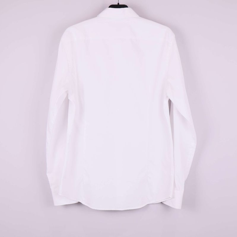 Baksidan på vit långärmad skjorta visas mot ljus bakgrund