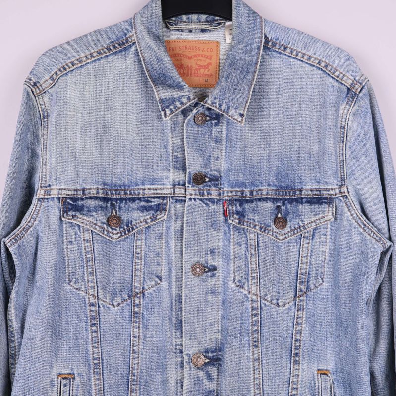 Närbild av överdelen och bröstfickor på ljus jeansjacka