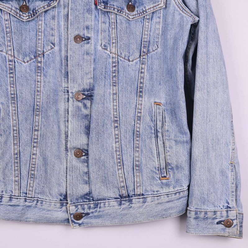 Närbild på nederdel och ärmslut av jeansjacka med knappar