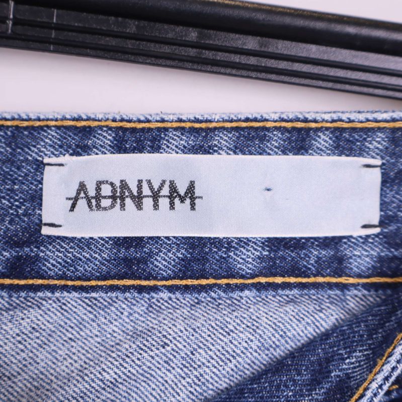 Närbild på vit etikett med tryckt logotyp adnym på jeansens insida