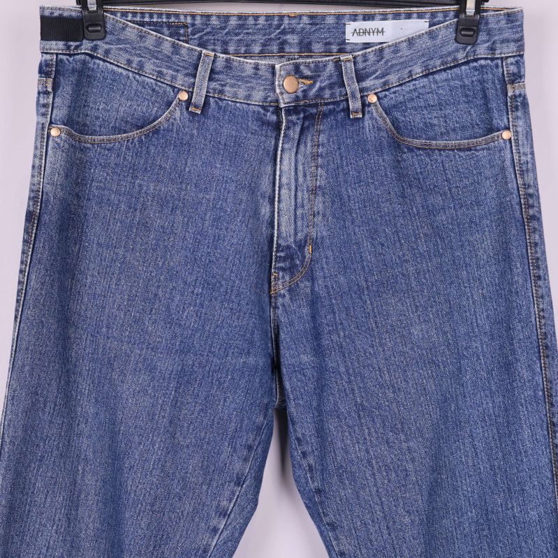 Närbild på jeansens midja, bälteshällor och knäppning