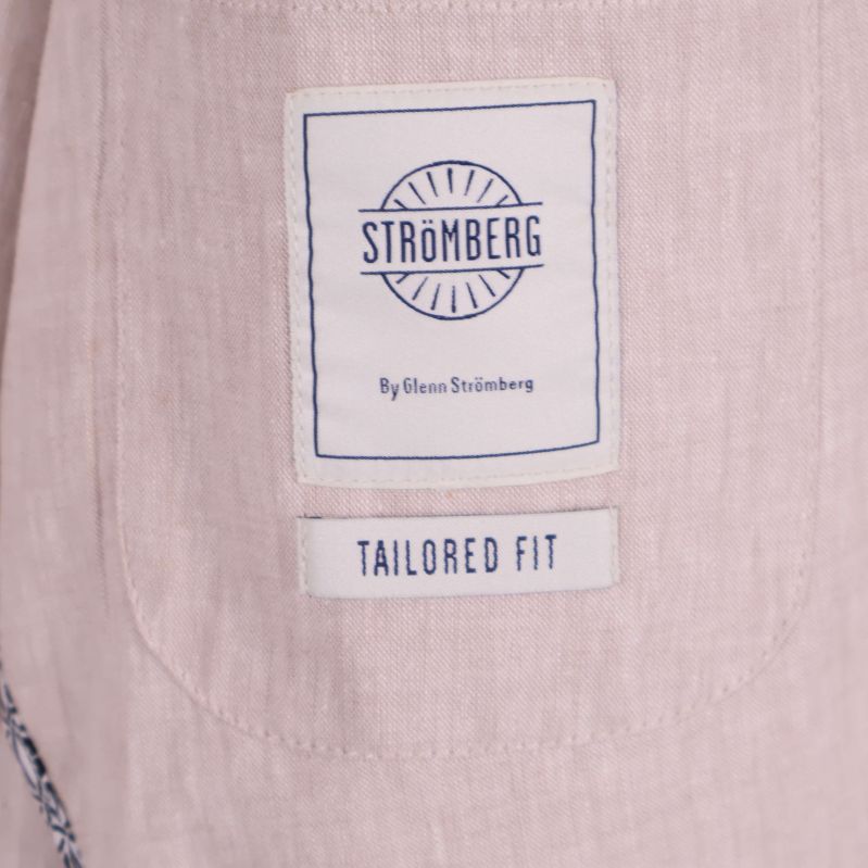 Logolapp Strömberg och text Tailored Fit på ljusbeige tyg