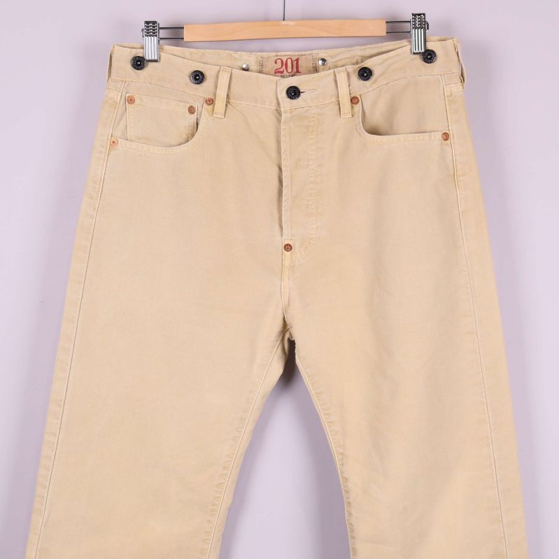 Närbild på framsidan av beige jeans och fickdesign