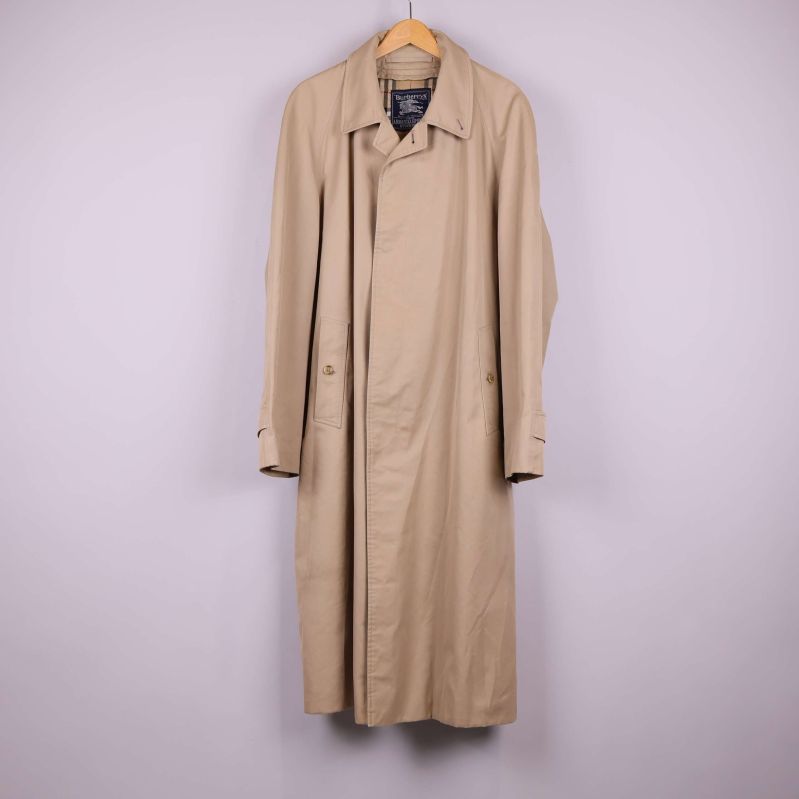 Beige lång trenchcoat på galge mot ljus bakgrund