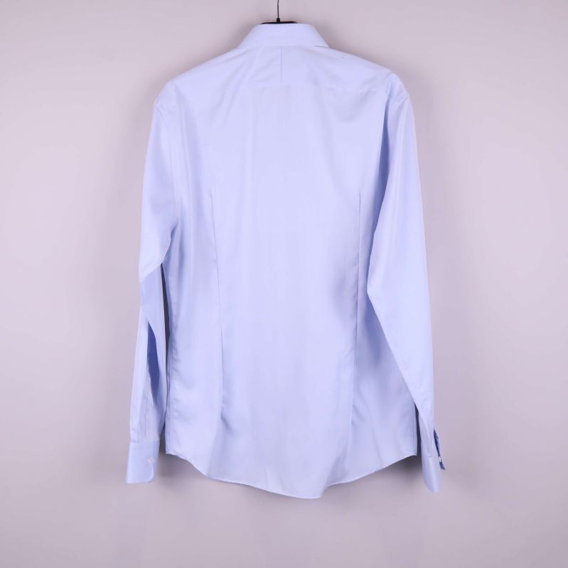 Baksidan av ljusblå skjorta visas mot ljus bakgrund