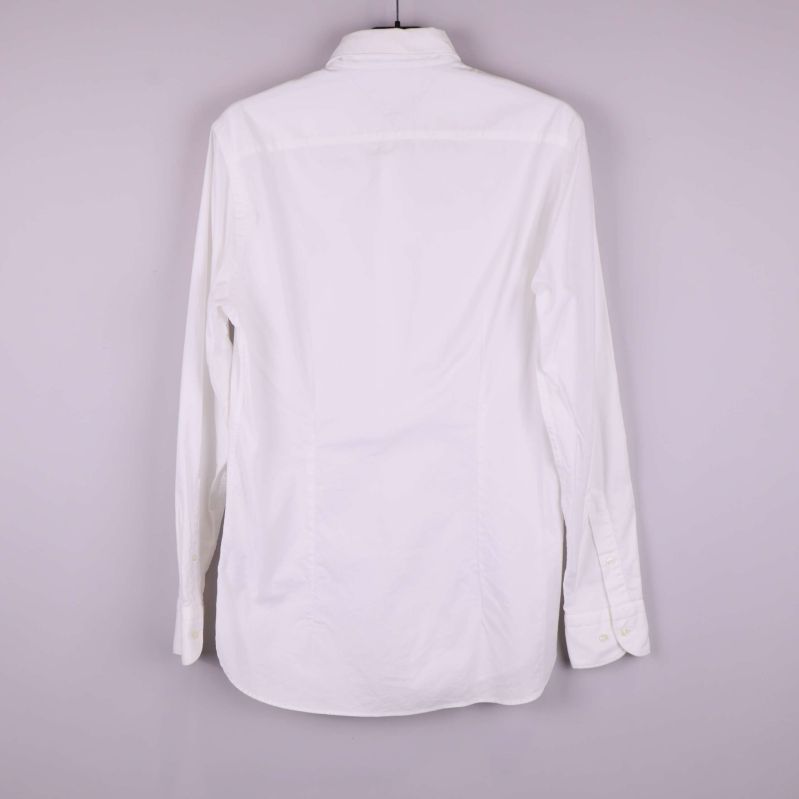 Baksidan av vit skjorta visas hängande på galge