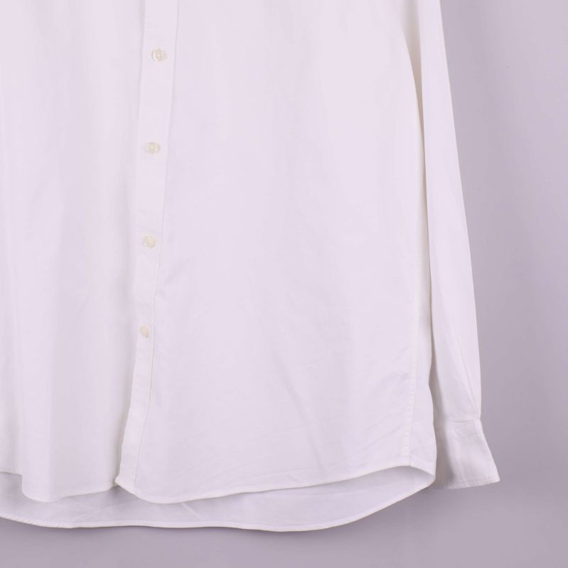 Närbild på skjortans nederkant och ärmslut i vitt tyg