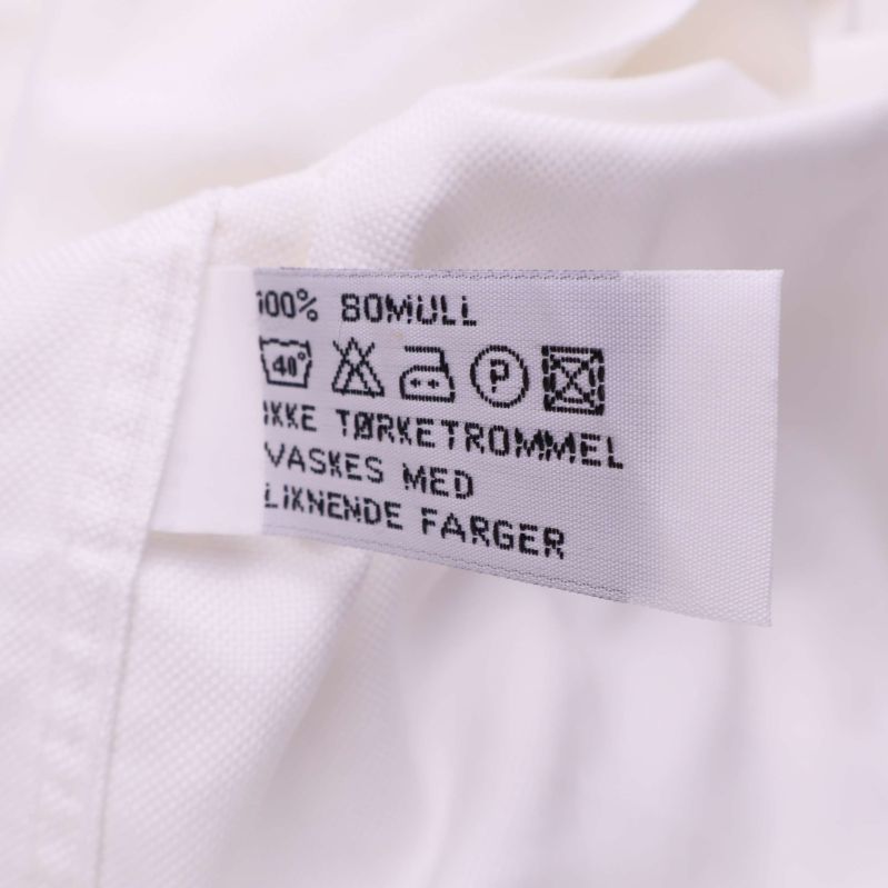 Tvättrådsetikett som visar 100% bomull och tvättrådssymboler