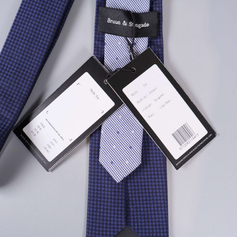 Två tags med text och streckkod fastsatta i slipsen