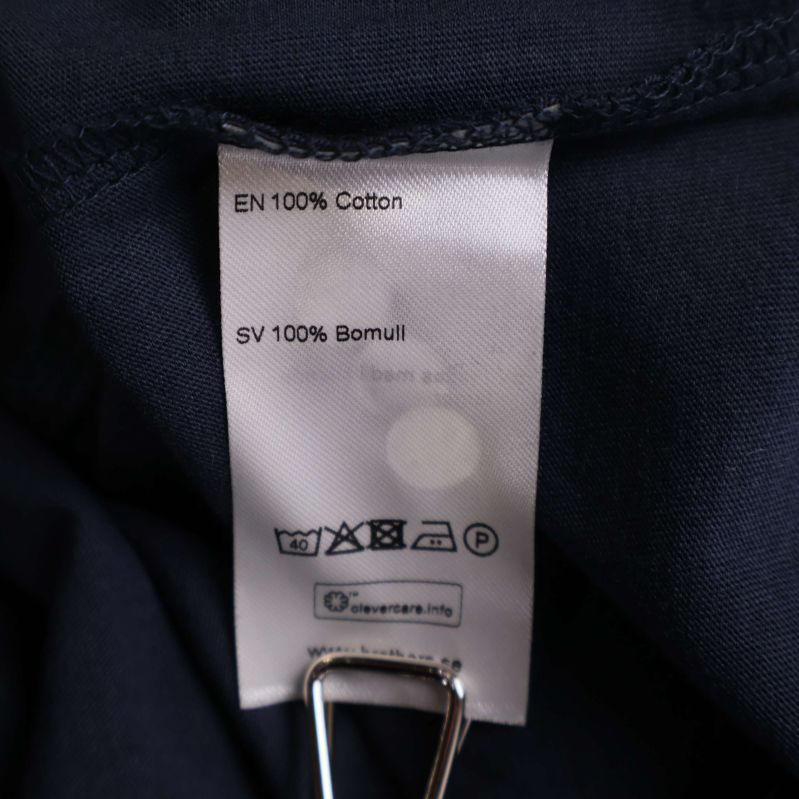 Materiallapp visar 100% bomull på flera språk