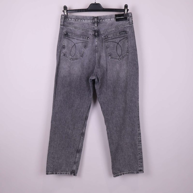 Baksida av grå jeans med dekorativa sömmar på fickorna