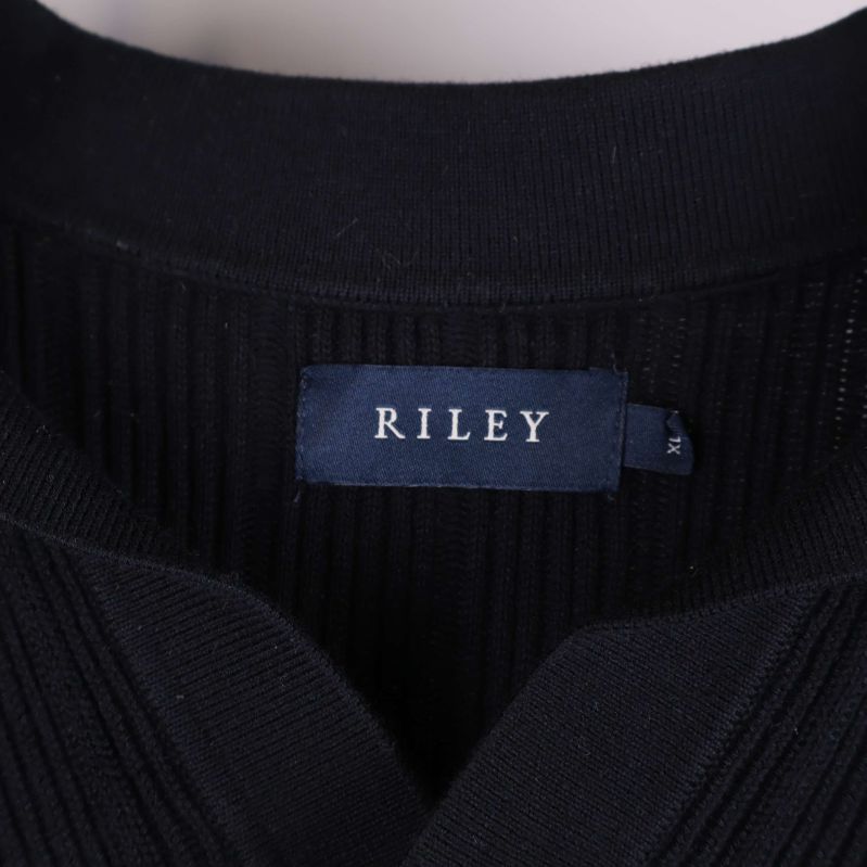 Närbild på RILEY-märke i krage på svart stickad tröja
