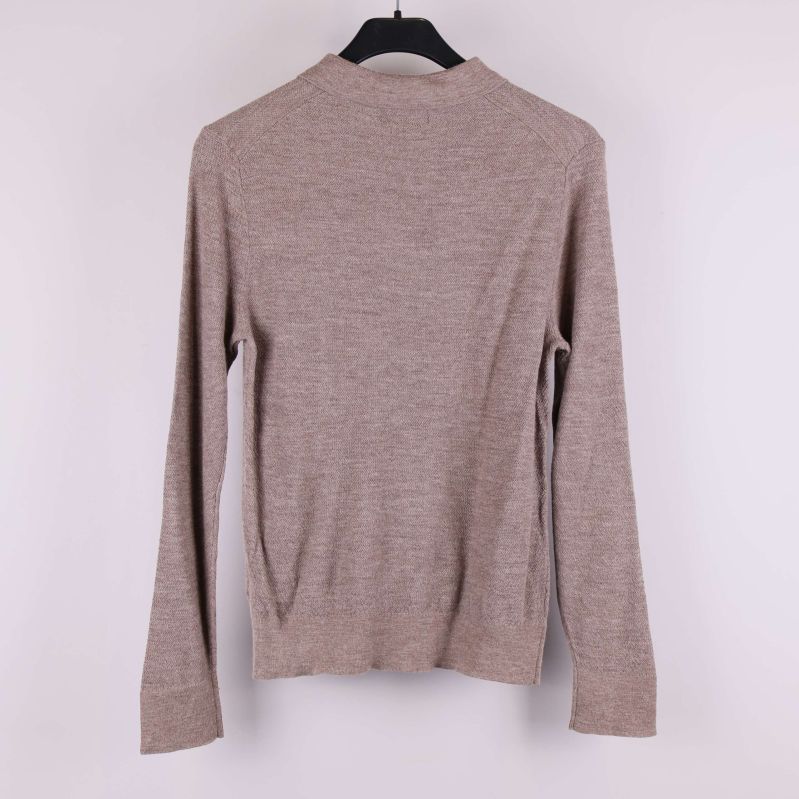 Baksidan av beige stickad tröja med långa ärmar