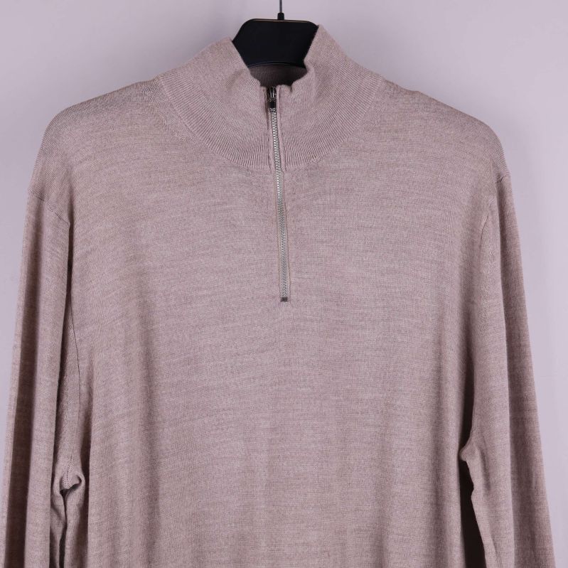 Närbild på dragkedja och halvpolo av beige stickad tröja