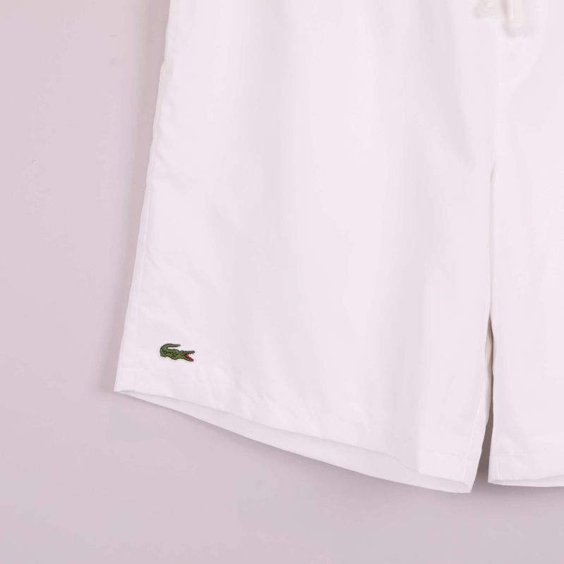 Närbild på Lacoste-logo broderad på vänster ben