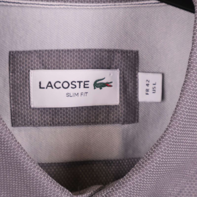 Närbild på Lacoste-märkesetikett och storleksskylt inuti skjortan