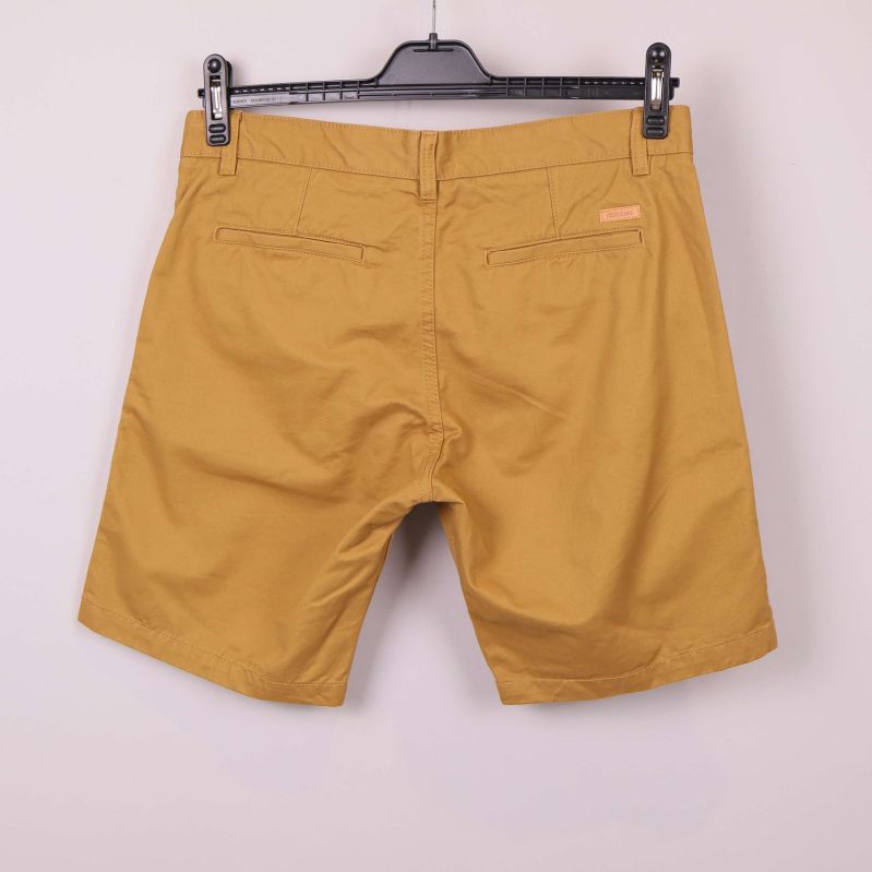 Baksida av gula chinoshorts med två bakfickor