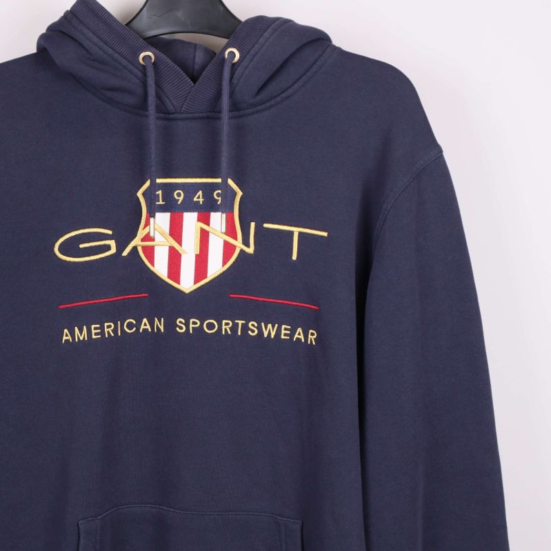 Närbild på logotyp och tryckdetalj framtill på mörkblå hoodie