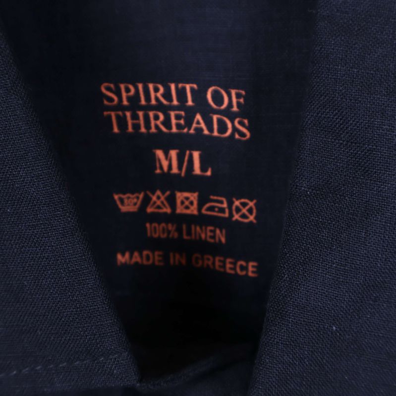 Närbild på etikett med texten Spirit of Threads och 100% linne
