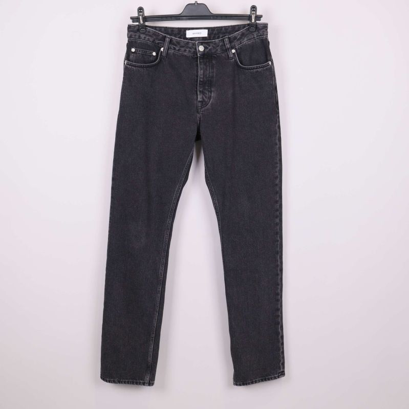 Framsida av svarta raka jeans hängande mot ljus bakgrund